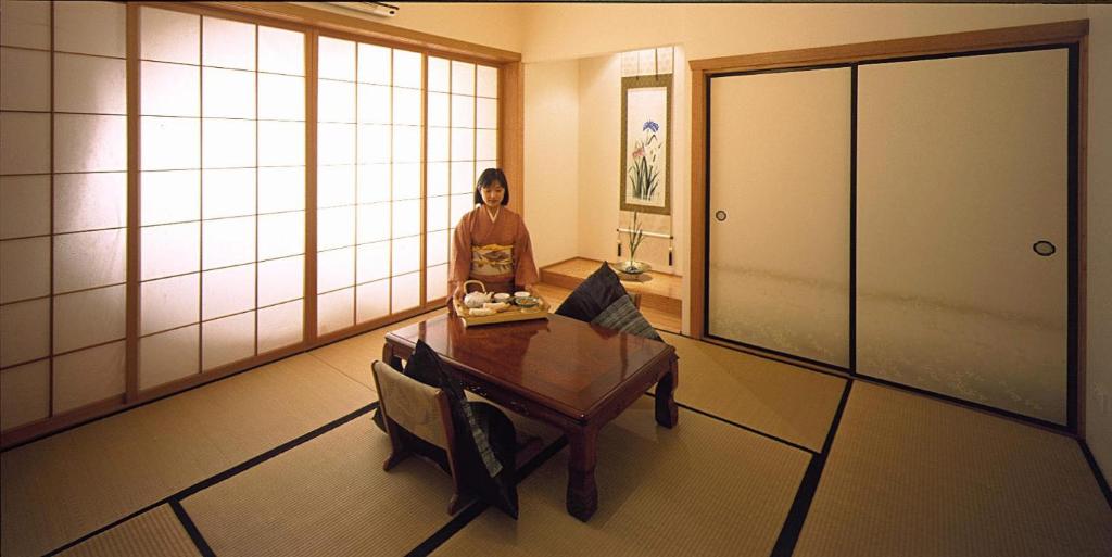 赫本温泉日本静香乡村旅馆Spa&健康胜地的坐在一个房间里桌子上的女人
