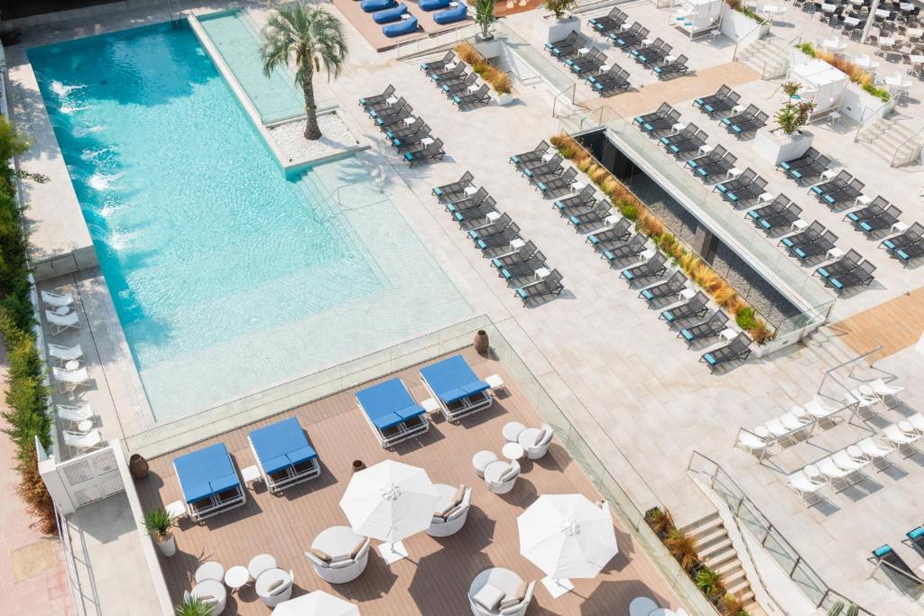 罗列特海岸L'Azure Hotel 4* Sup的享有带椅子和遮阳伞的游泳池的上方景致