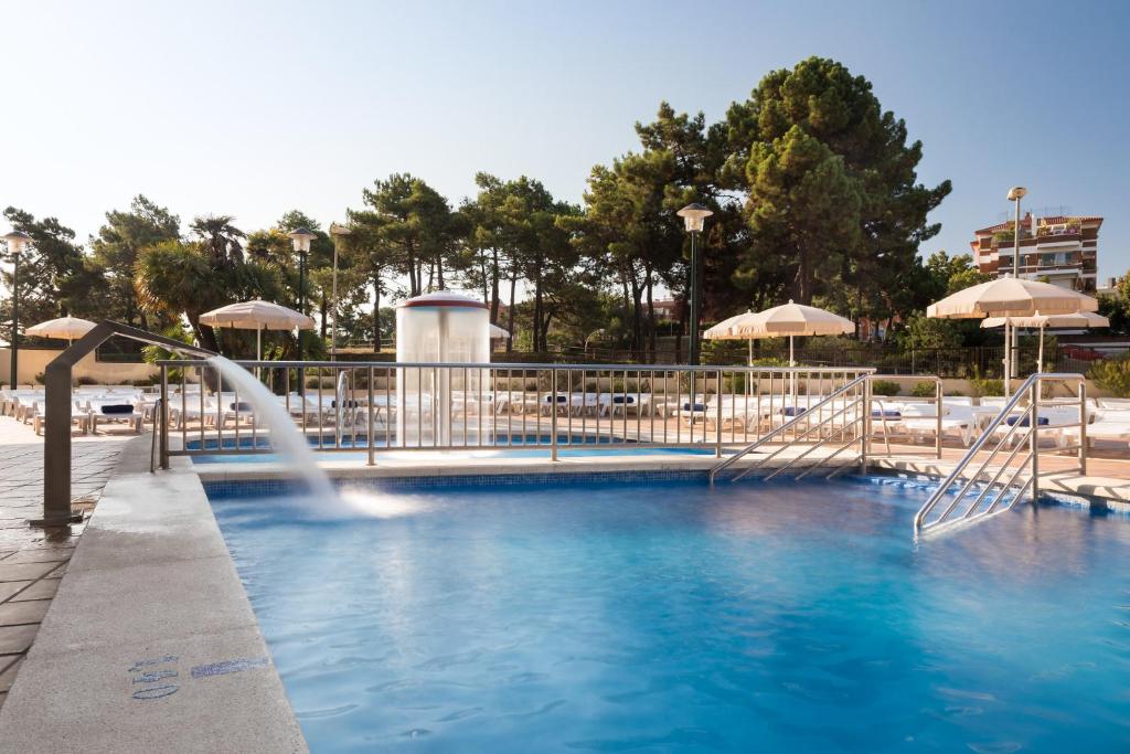 罗列特海岸htop Royal Star & SPA #htopFun的一个带喷泉和遮阳伞的游泳池