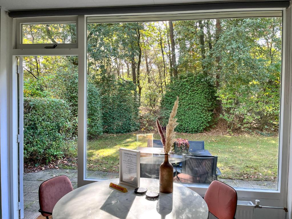 奥特罗Modern natuurhuisje midden in het bos op de Veluwe - Beau Home的窗前的桌子上有一个花瓶