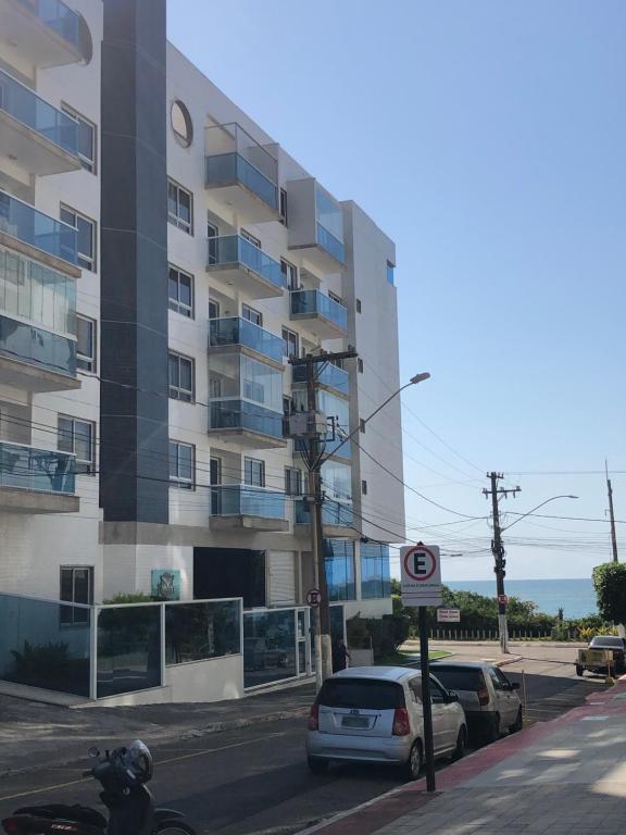 瓜拉派瑞Apartamento peracanga com vista para o mar的公寓大楼前面设有停车位。