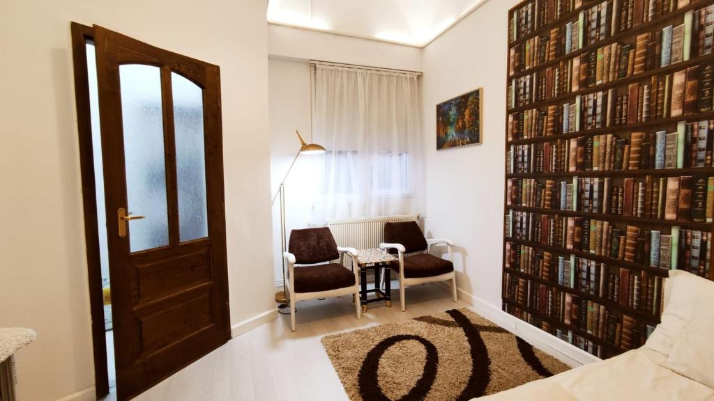 克卢日-纳波卡Cluj Center的一间设有桌子和两把椅子及书墙的房间