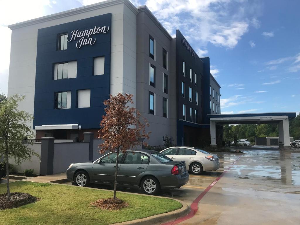 朗维尤Hampton Inn Longview的两辆车停在停车场的大楼