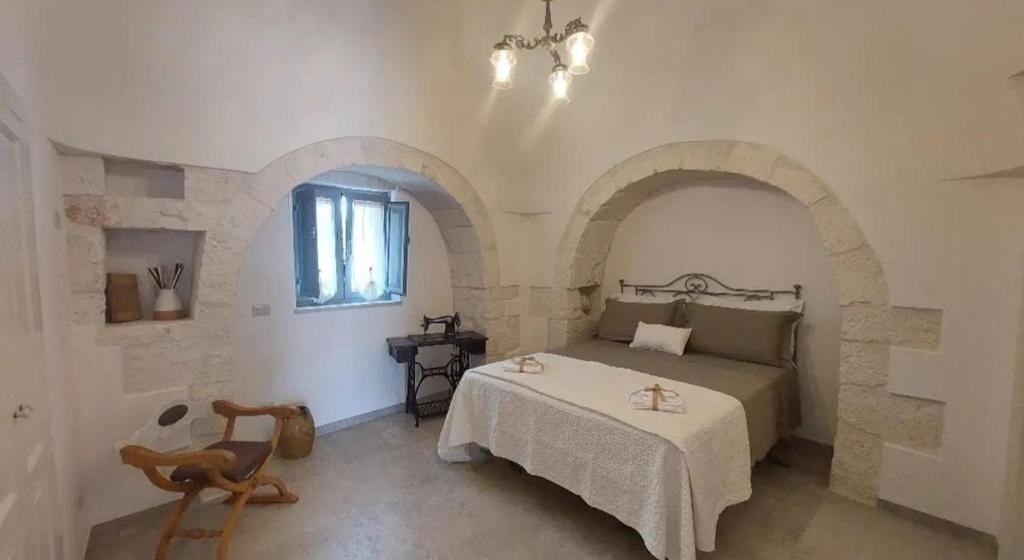 奇斯泰尼诺Trullo La chicca della valle的一间带一张床铺的卧室,位于带拱门的房间