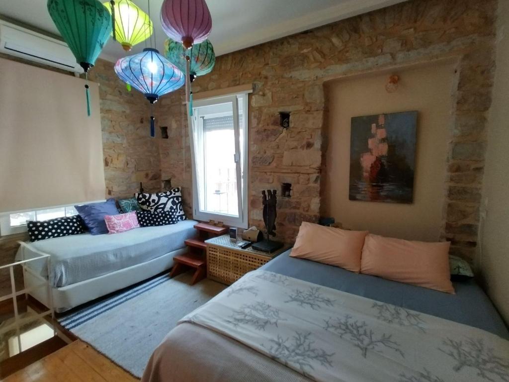 希俄斯MASTIXI Colors的一间卧室配有两张床、一张沙发和吊灯。