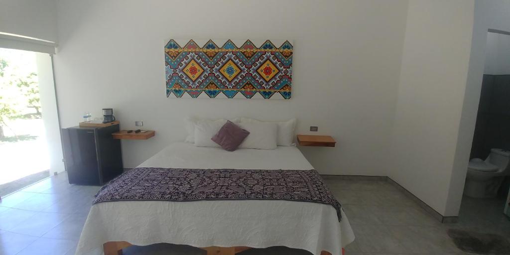 圣玛丽戴尔奥罗Hotel Lucero Chan的卧室配有一张床,墙上挂有绘画作品