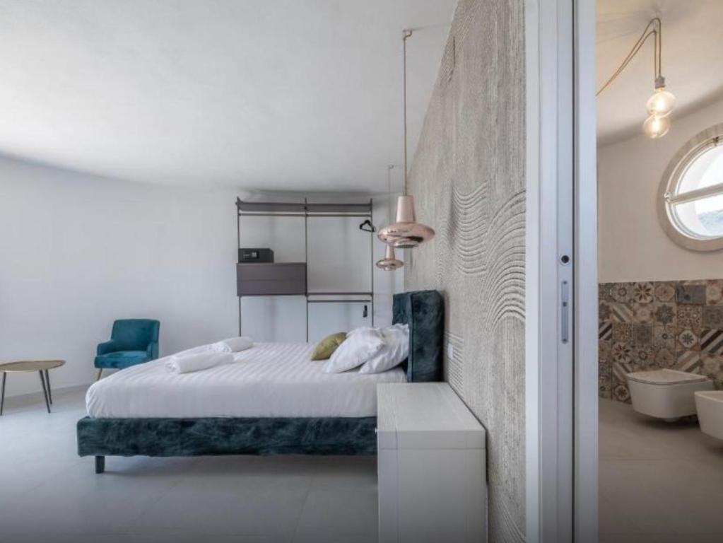 哥斯达雷Villa Escargot Luxury in Costa Rei Beach的白色卧室配有床和蓝椅