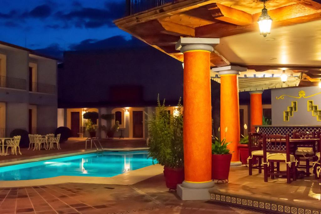 瓦哈卡市圣埃伦娜广场酒店的一座带橙色柱子和桌椅的度假游泳池