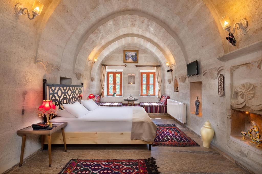 阿瓦诺斯HacıAşık Konağı Butik Hotel的卧室配有一张白色大床,位于石墙内