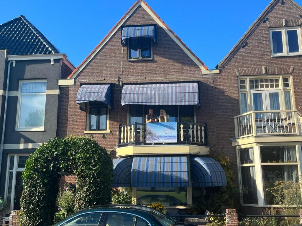 海边的艾格蒙特B&B de Zandtaart的带阳台的房子,上面有两只狗