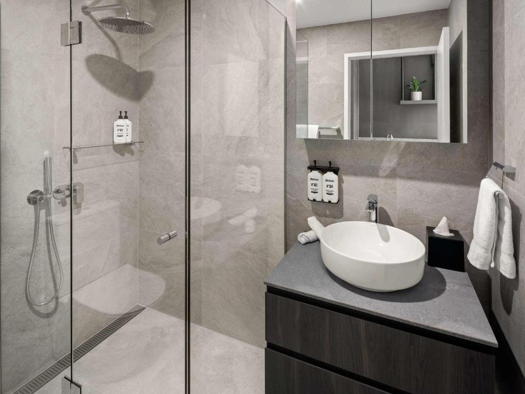 堪培拉The Sebel Canberra Campbell的一间带水槽和玻璃淋浴的浴室