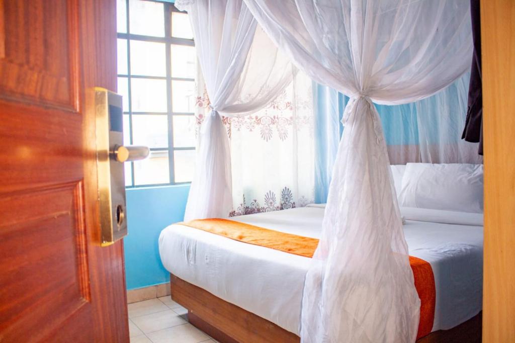 内罗毕Deka Self Contained Rooms的一间卧室配有一张天蓬床和窗户