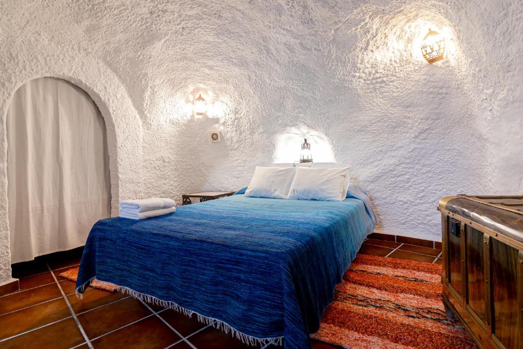 格拉纳达Cuevas El Abanico - VTAR vivienda turística de alojamiento rural的一间白色客房内的蓝色床卧室
