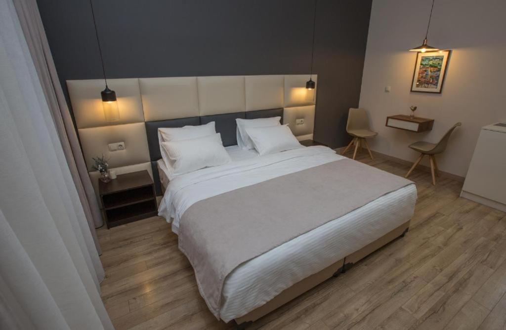 第比利斯History Hotel Tbilisi的卧室配有一张带白色床单和枕头的大床。