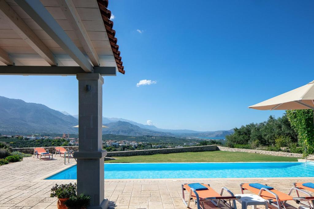 埃皮斯科皮Villa Luni的享有带椅子和遮阳伞的游泳池的景色