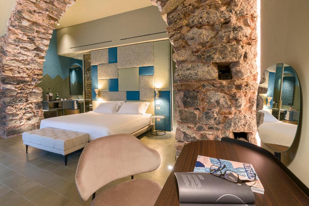 卡塔尼亚BASTIÒ PRIVATE SUITES的酒店客房,设有床铺和石墙