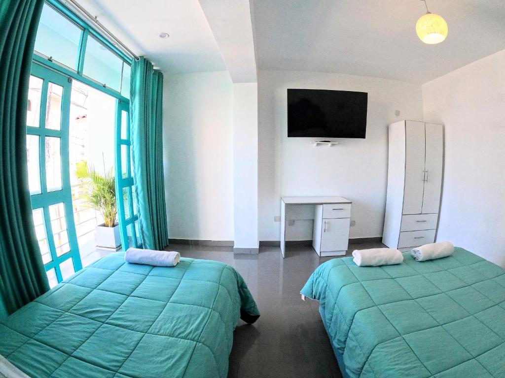 帕拉卡斯AQUAMARINE PARACAS Beach Hostal的一间卧室设有两张床、一台电视和一扇窗户。