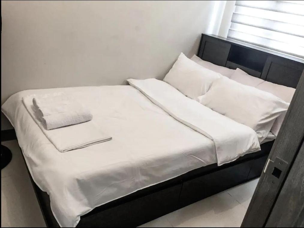 马尼拉StayInMyCondo - 8th Condo in Pasay near NAIA Airport, MOA Pasay的一张带白色床单和枕头的床