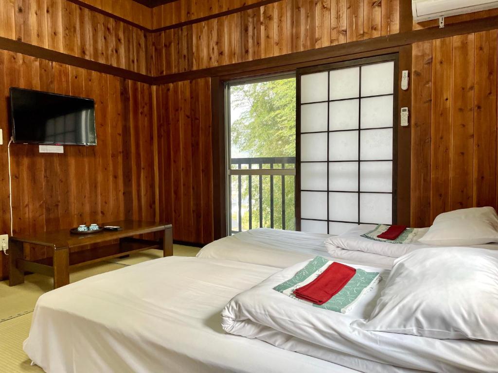 由布市旅館 竹屋 Takeya的一间卧室设有两张床、一台电视和一扇窗户。