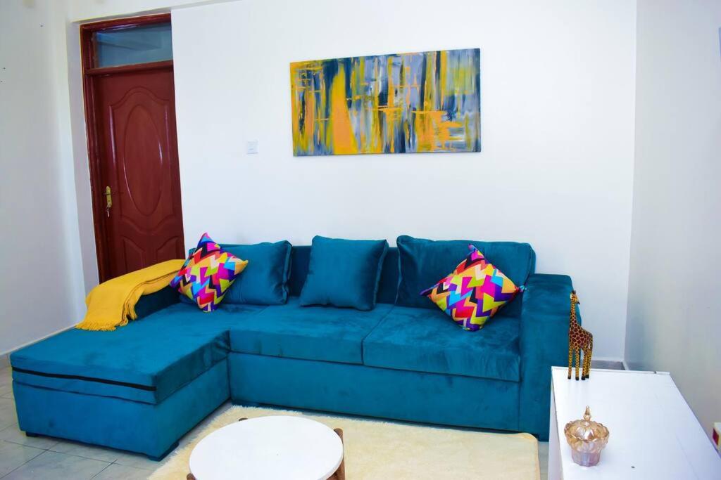 埃尔多雷特Rorot 2 bdrm stay located Annex home away(bright)的客厅里配有带色彩缤纷枕头的蓝色沙发