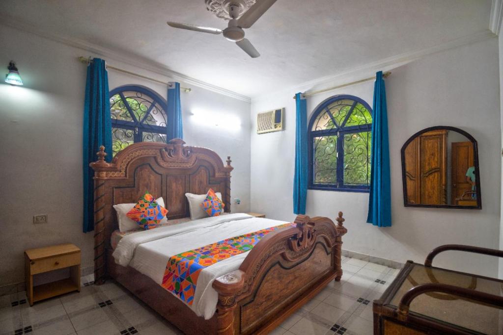 果阿旧城Hilltop 4BHK Villa with Private Pool Near Candolim的一间卧室配有一张带蓝色窗帘的大型木床。
