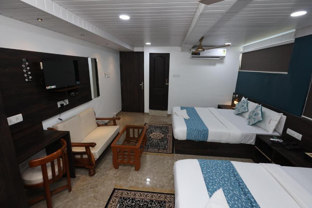 孟买HOTEL ASTROS的酒店客房配有两张床、一张沙发和一张书桌。