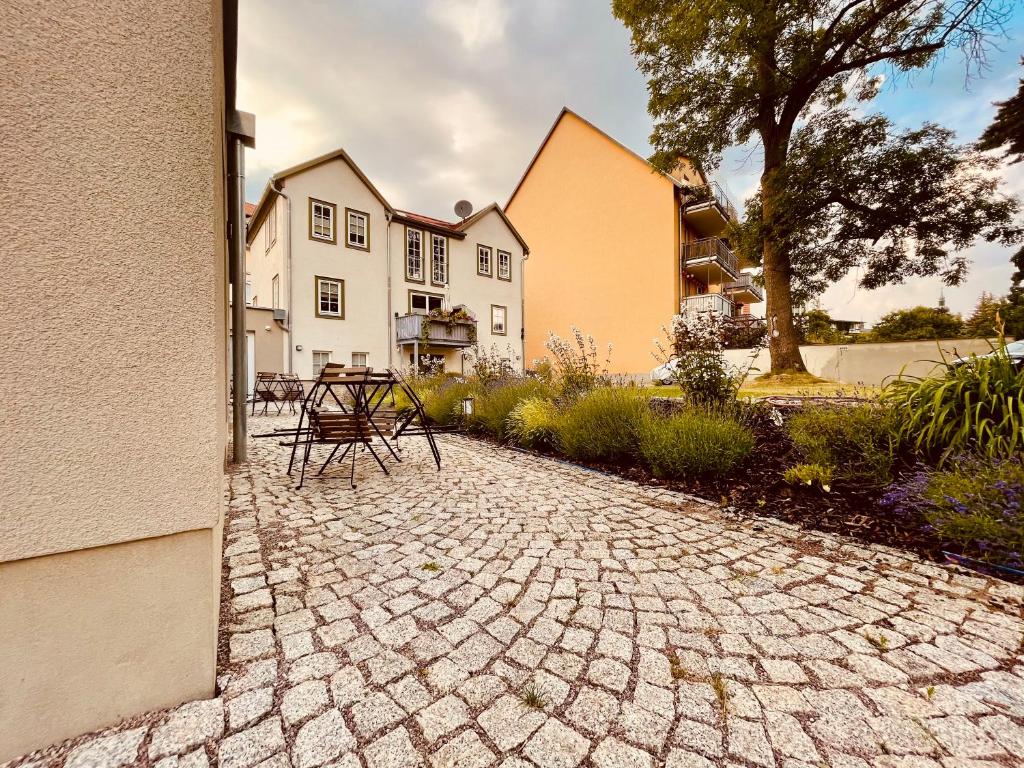 爱尔福特Ferienwohnungen Mey Haus zum Rosenstock的桌子和椅子坐在房子前面的石头庭院