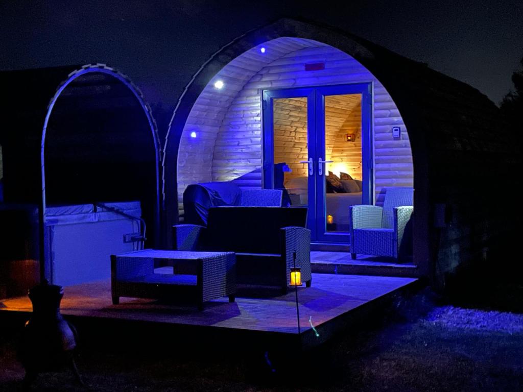 约克Little Meadow Pods with Hot Tub的一间黑暗的房间,在帐篷里配有沙发和椅子