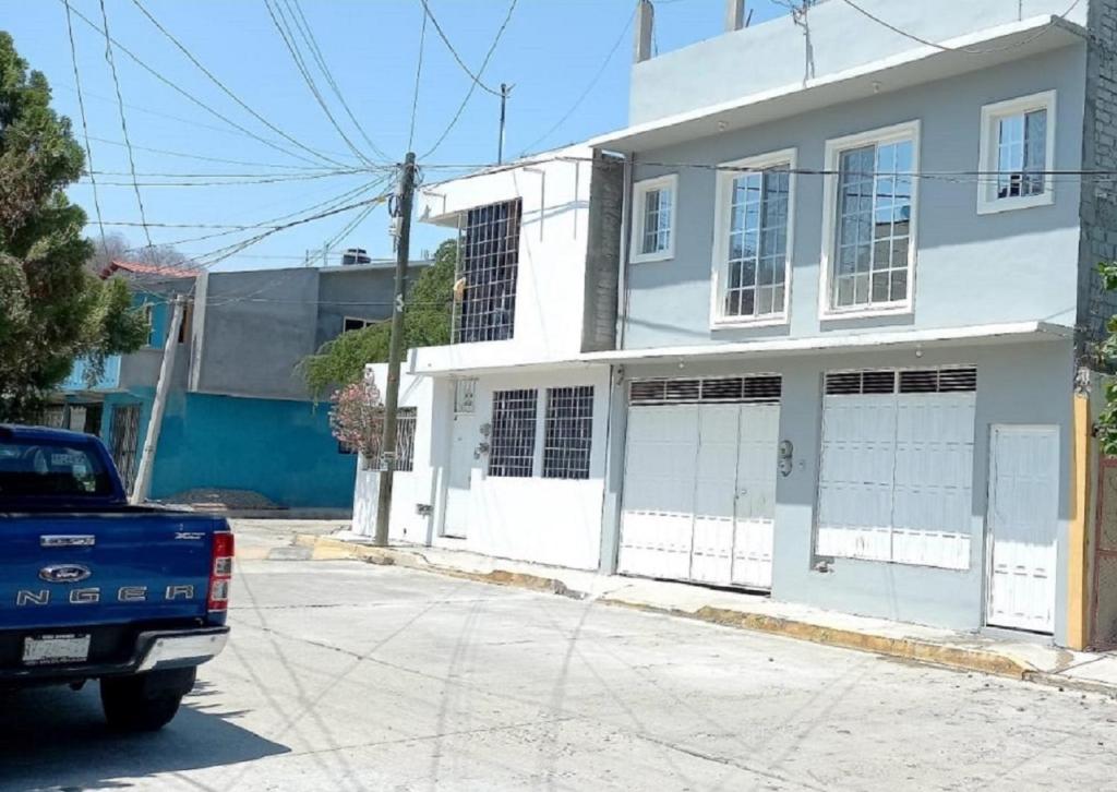 圣克鲁斯华特库Departamento ELSA. La Crucecita, Huatulco.的停在白色房子前面的一辆蓝色卡车