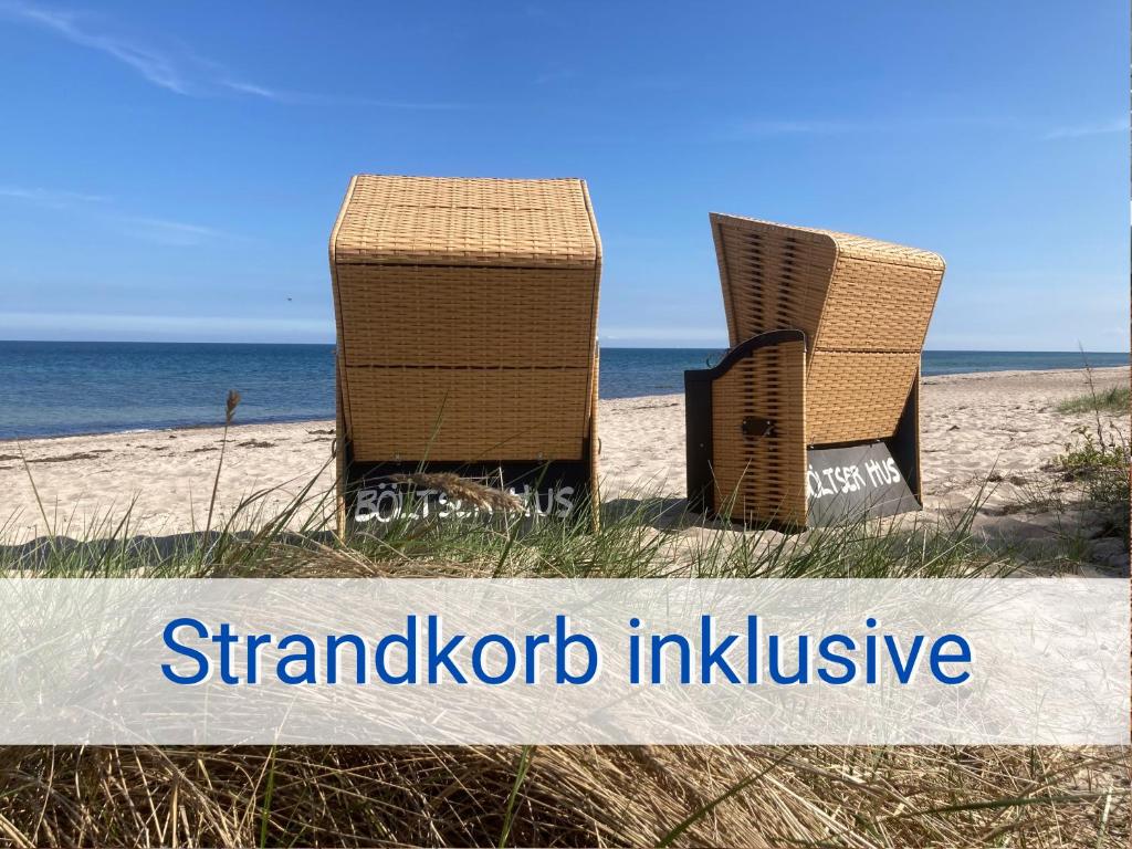 NeukirchenBöltser Hus Ferienwohnungen mit Strandkorb und Kamin 10 Gehminuten zum kurtaxefreien Sandstrand的两把椅子坐在海边