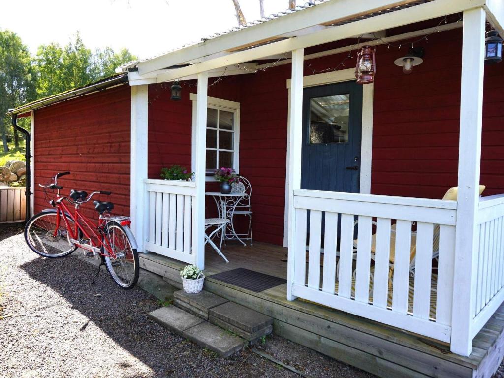 HögsjöHoliday home Högsjö的一座红色的房子,有一辆自行车停在门廊上