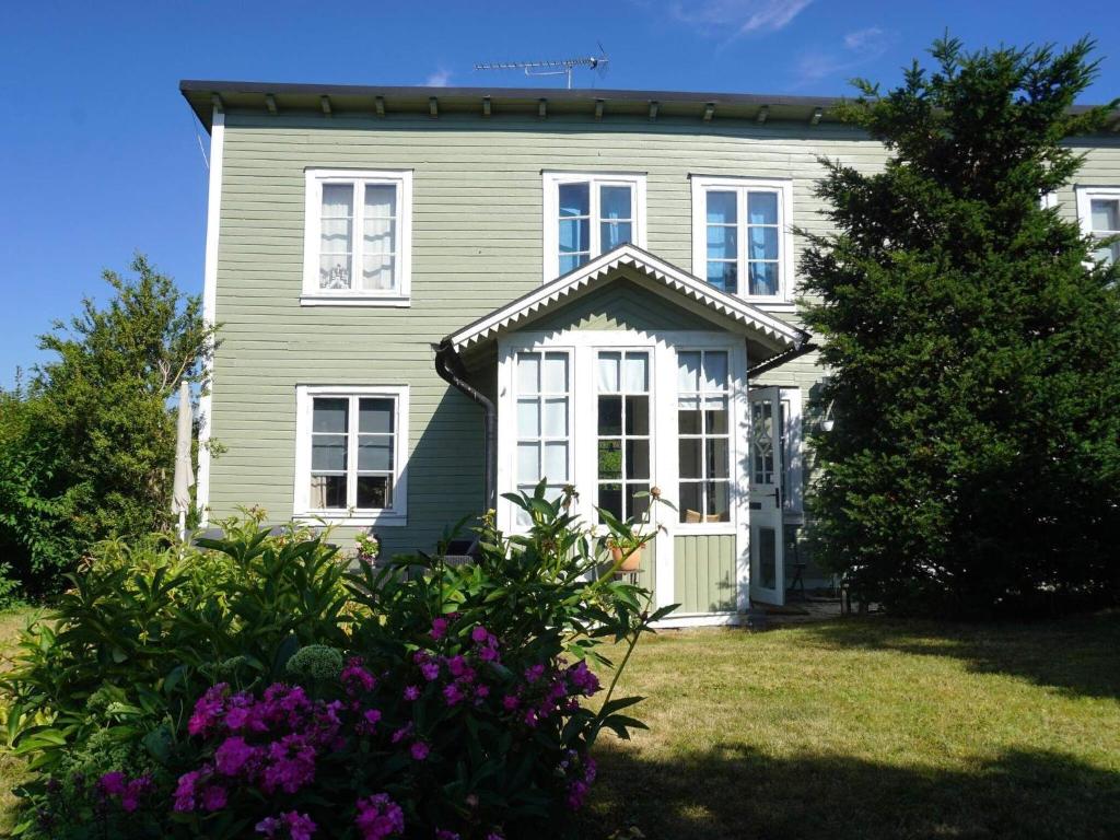 龙讷比Holiday home RONNEBY IX的绿色房子,设有白色窗户和紫色的鲜花