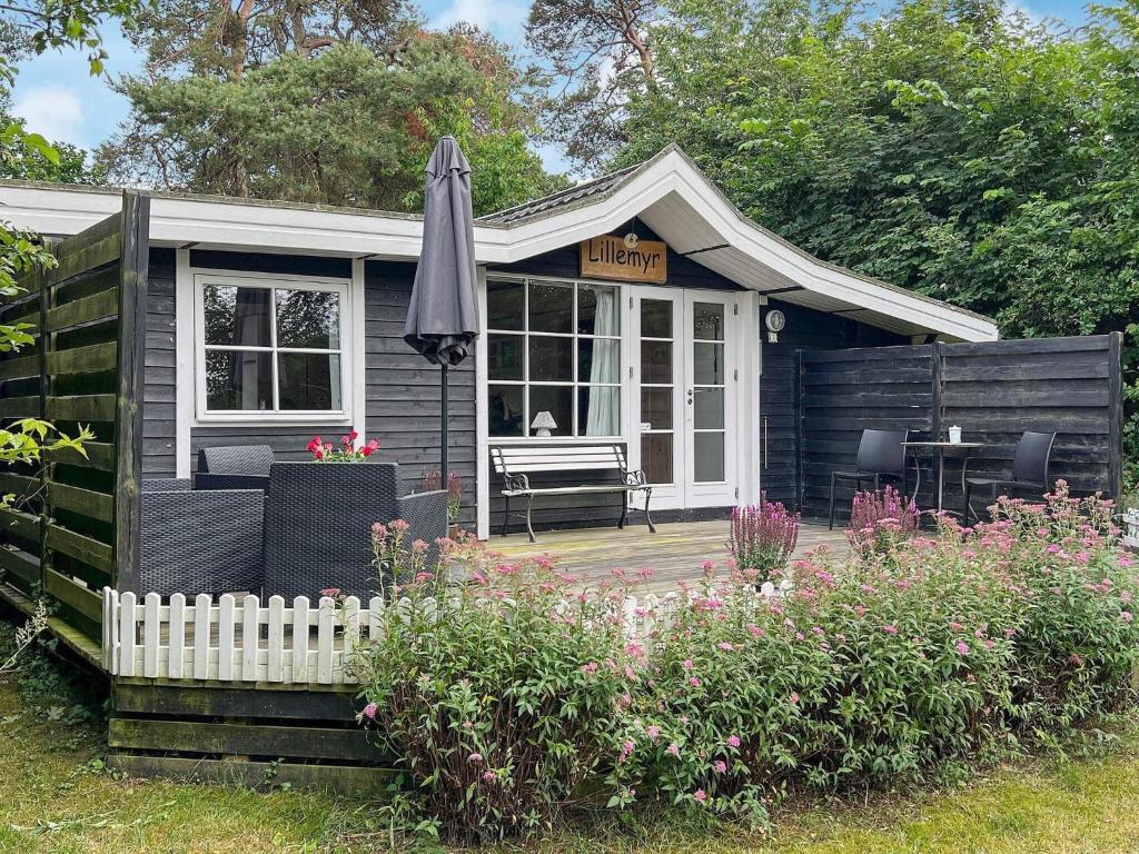 内克瑟Holiday home Nexø XLI的一座带遮阳伞和庭院的小房子