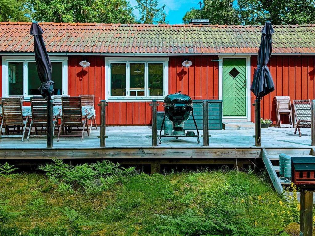 GustavsvikHoliday home SALTSJØBO的红色的房子,配有带椅子和遮阳伞的甲板