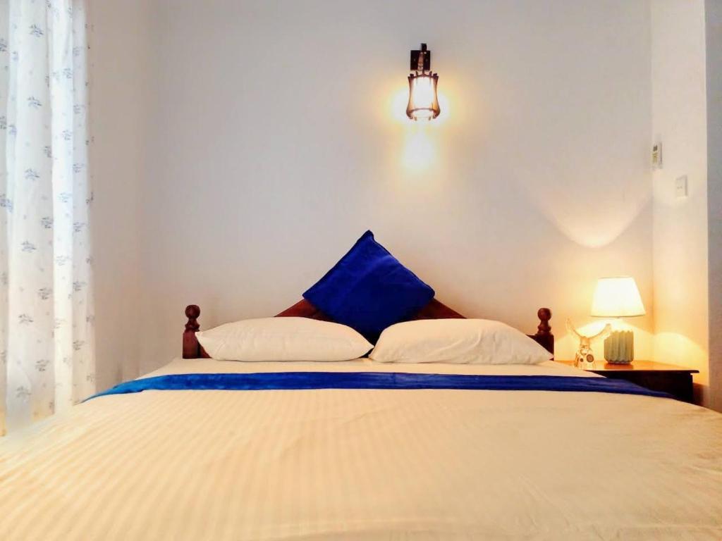 尼甘布The Tourist Balcony的卧室配有白色床和蓝色枕头