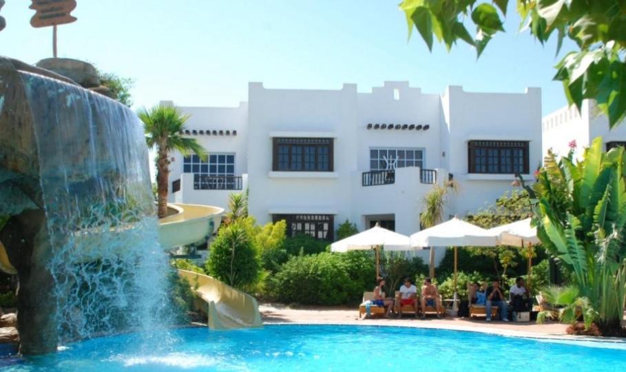 沙姆沙伊赫Delta Sharm appartment Shahrazad的一座大楼前的游泳池,带喷泉