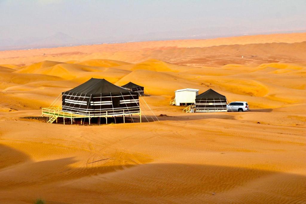 BadīyahRashid Desert Private Camp的一群帐篷在沙漠中,有一辆白色汽车
