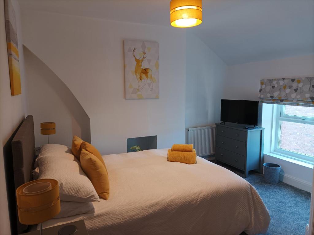 利物浦Victorian Renovation Room 8的一间卧室配有一张带黄色枕头的床和电视。