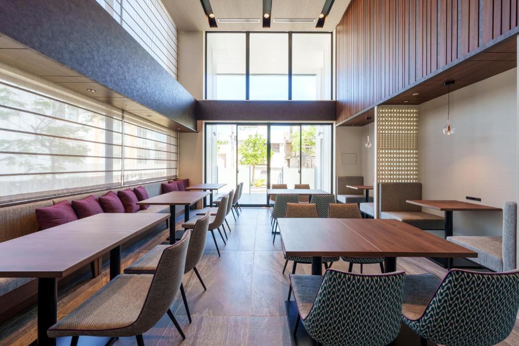 那霸Hotel GrandConsort Naha的餐厅设有木桌、椅子和窗户。