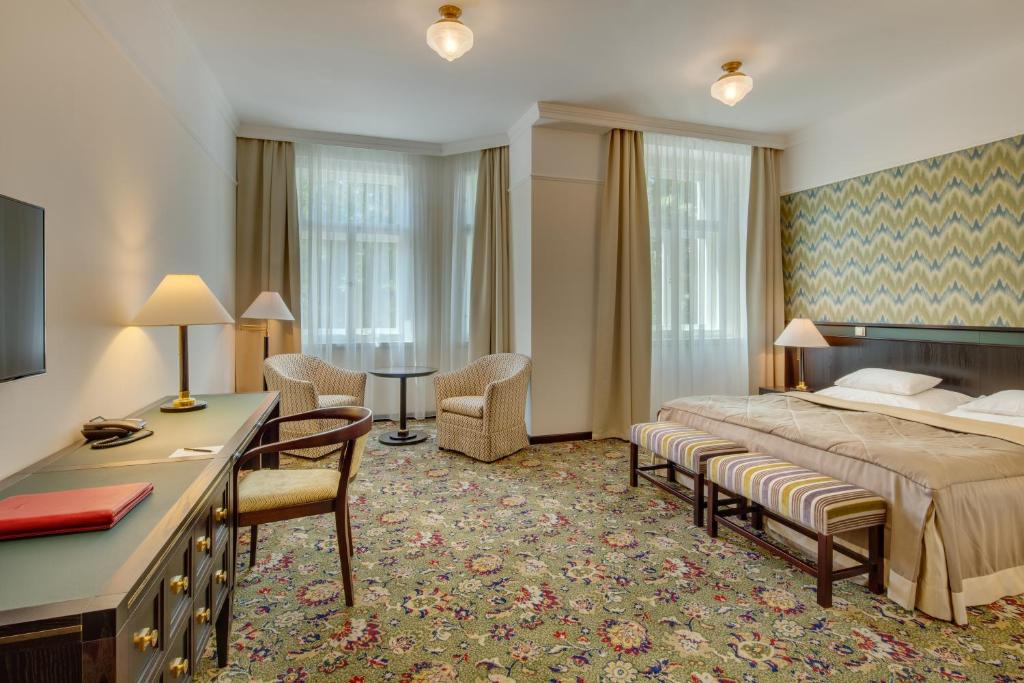 布拉格Hotel Savoy Prague的酒店客房,配有一张床、一张桌子和椅子