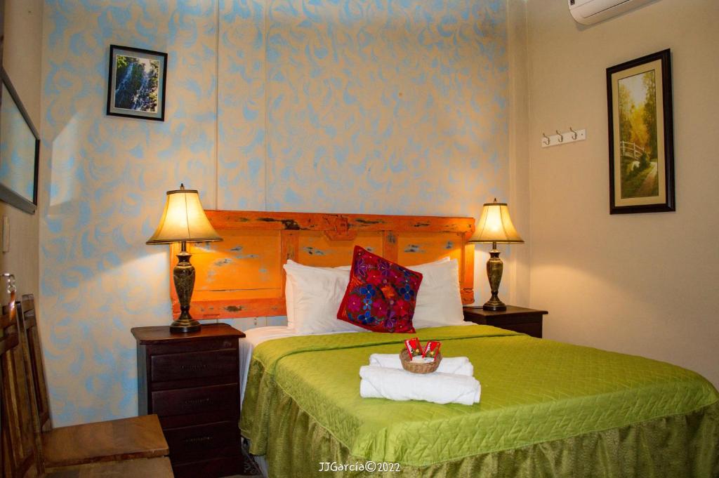 SuchitotoHostal Koltin Suchitoto的一间卧室配有一张带绿毯的床和两盏灯。