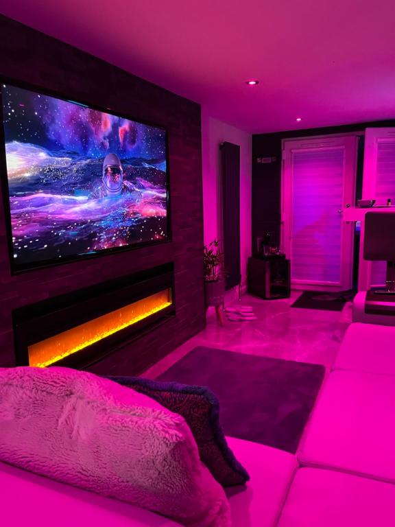 MurroesThe_Spa_Cave的客厅配有大电视和粉红色的灯光