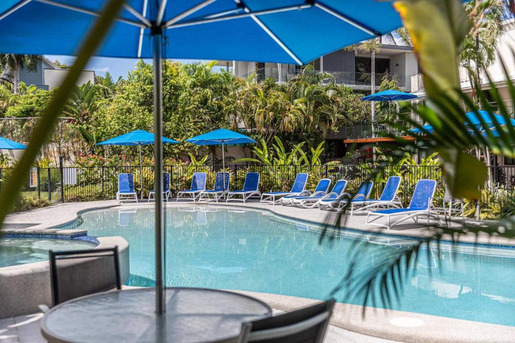 道格拉斯港Beachfront Terraces with Onsite Reception & Check In的一个带桌椅和蓝伞的游泳池