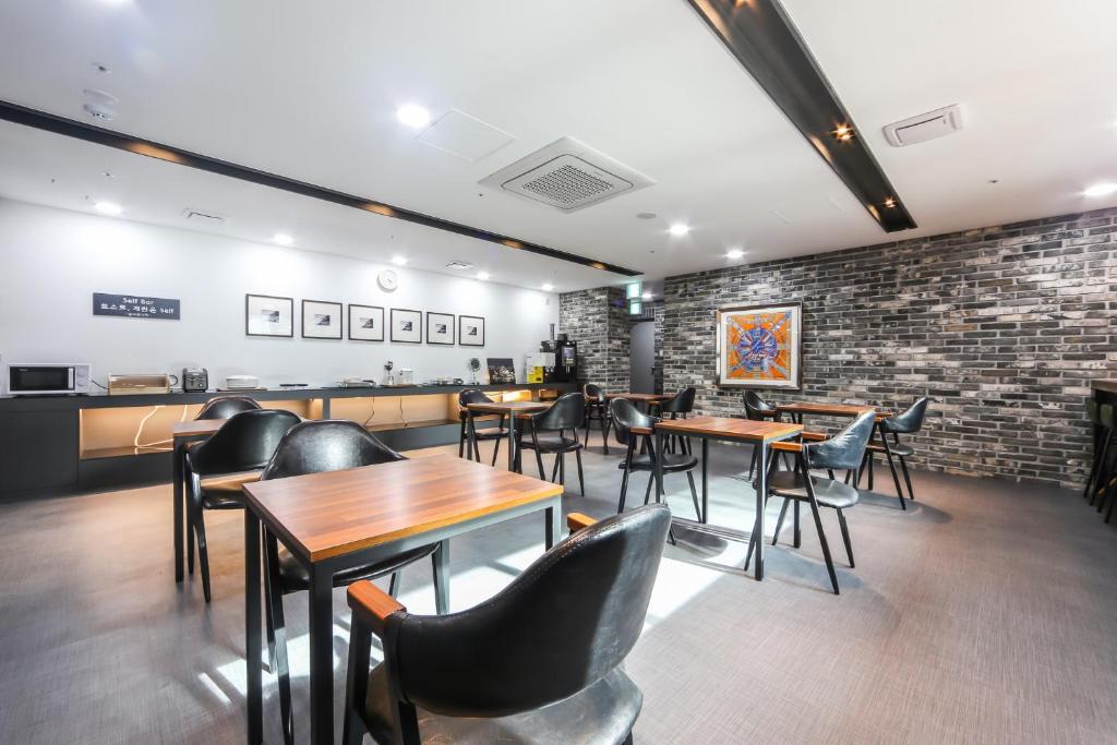 釜山Seomyeon Brown-dot hotel Gold的一间带桌椅的餐厅以及砖墙