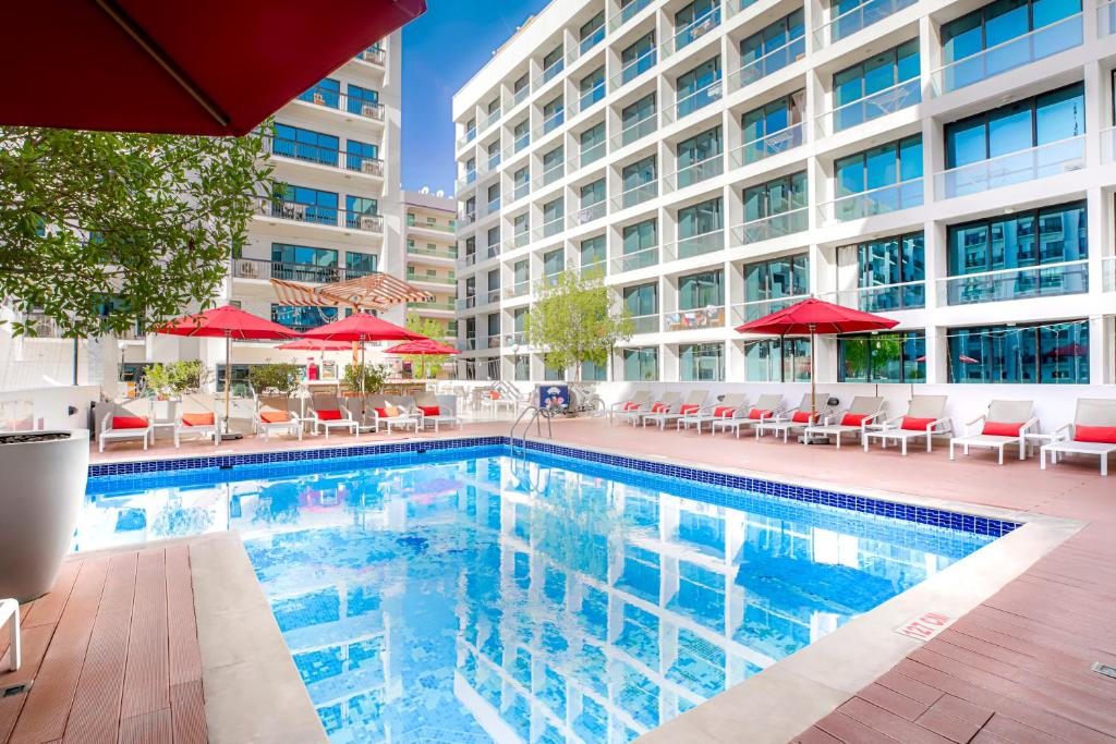 迪拜金沙公寓酒店的一个带红色遮阳伞的游泳池和一座建筑