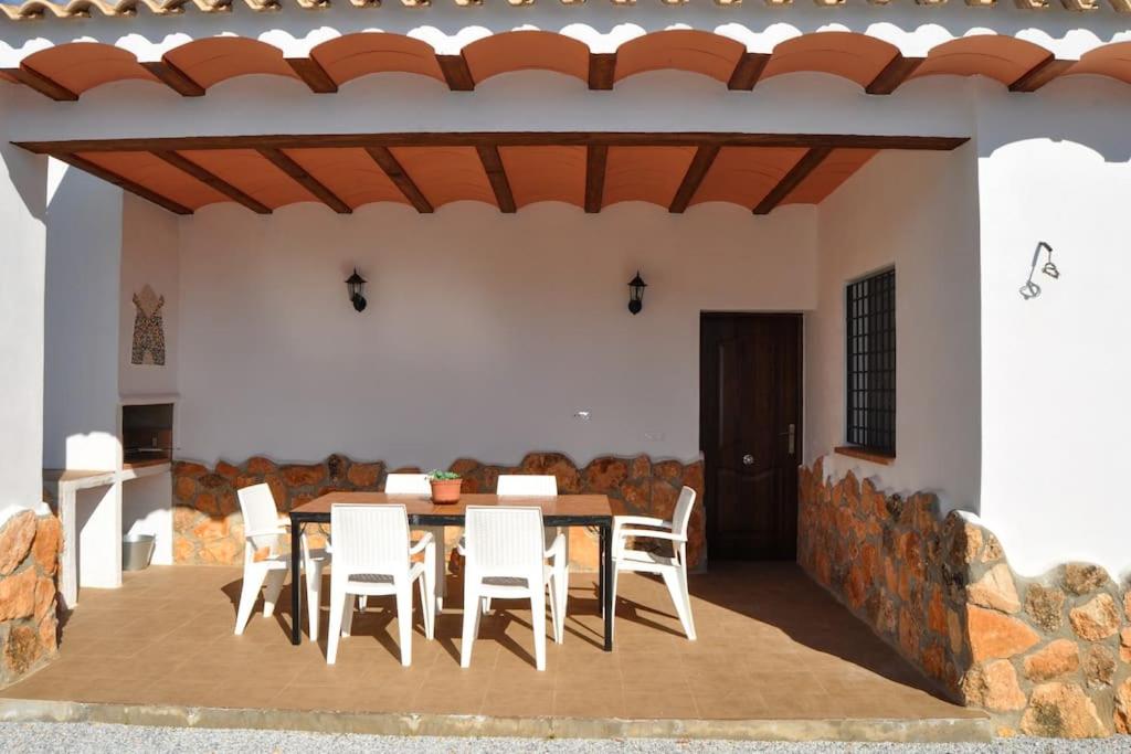 波索阿尔孔Casa rural Molino S CAZORLA PISCINA COMPARTIDA的庭院配有桌子和白色椅子