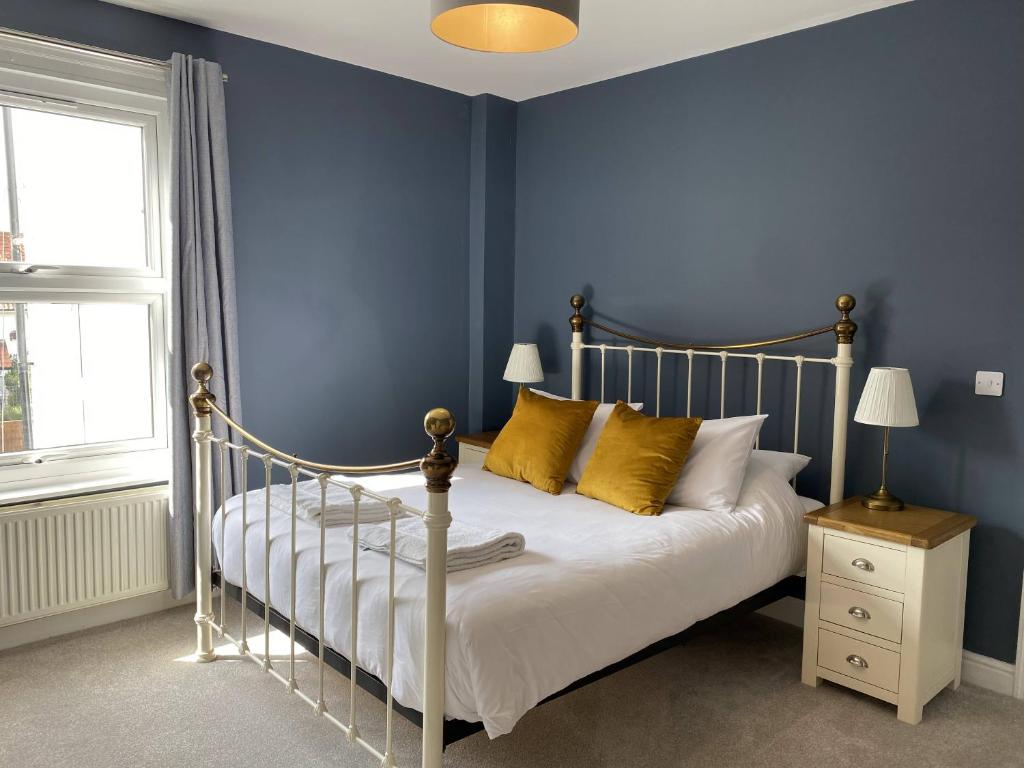 克罗默Coast House Cromer - Sleeps 15, hot tub, sea views的一间卧室拥有蓝色的墙壁,配有一张带黄色枕头的床。