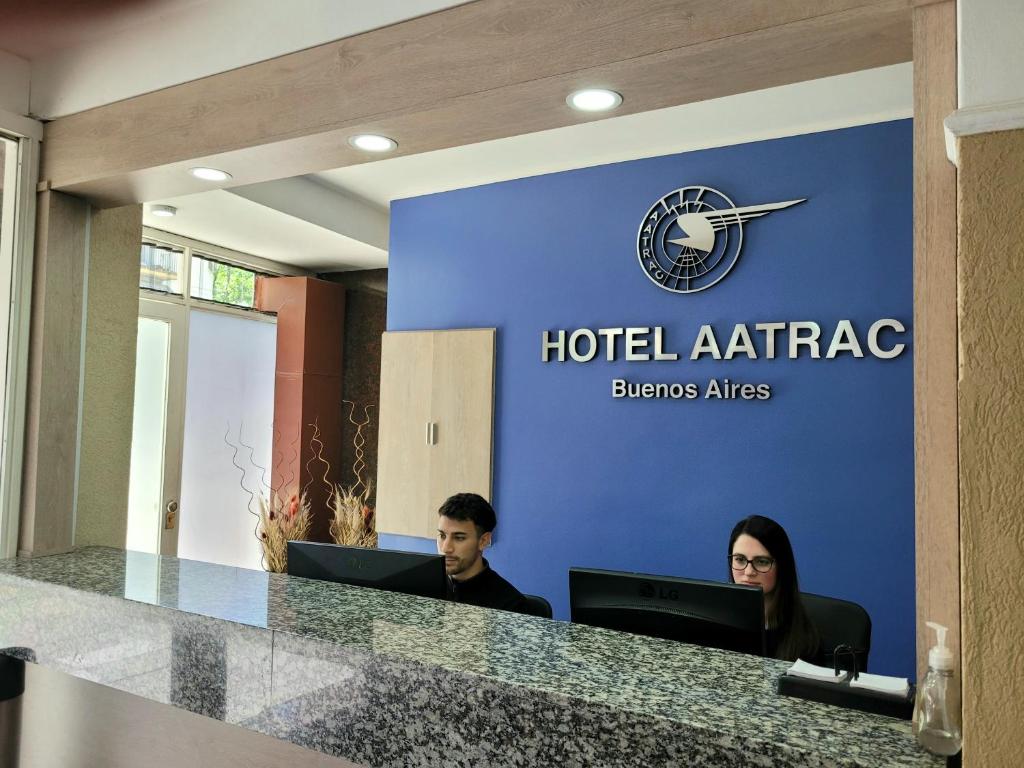 布宜诺斯艾利斯Hotel AATRAC Buenos Aires的两人坐在酒店办公室的办公桌上