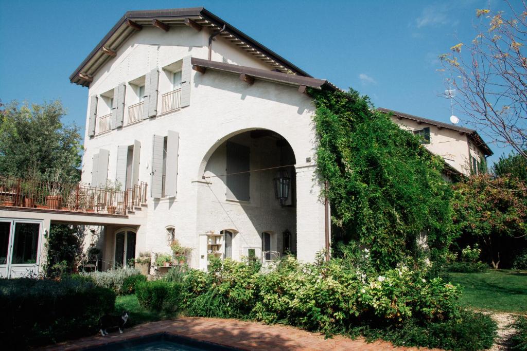 雷焦艾米利亚Casale Hortensia的一座带拱门和常春藤的白色房子