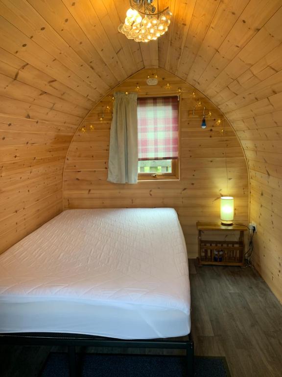 HullandPoplars Farm Site Glamping Pods的木制客房的一张床位,设有窗户
